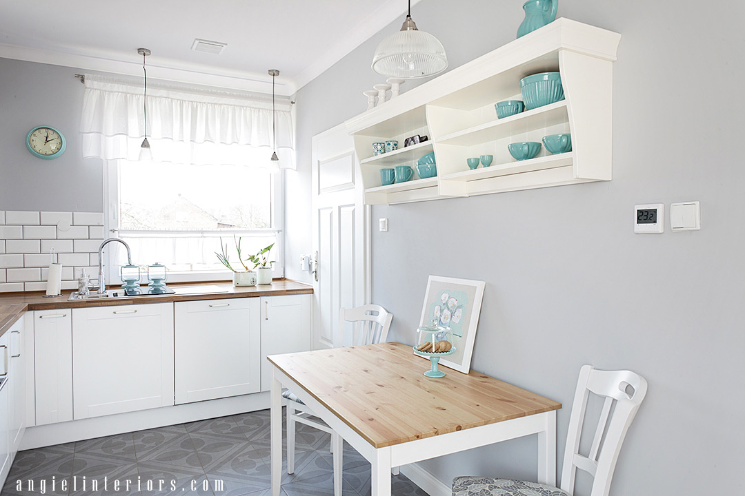 small kitchen with white cabinets, butchers block countertop, grey walls and patterned floor tiles ad turquoise accents