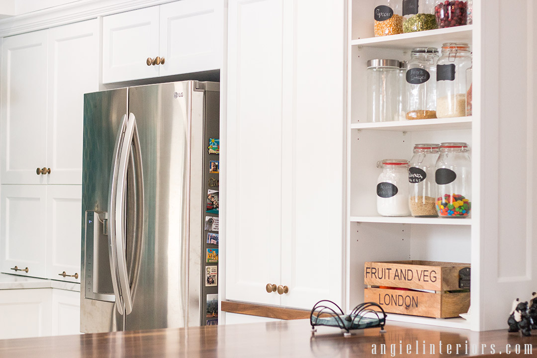 Shaker style cabinets with champagne gold hardware and open shelves over butcher's block counter