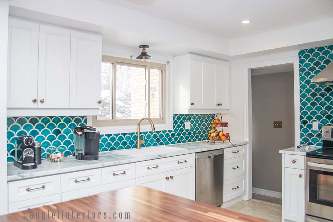 Fishscale teal tiles, white cabinets and champagne gold accents in modern kitchen