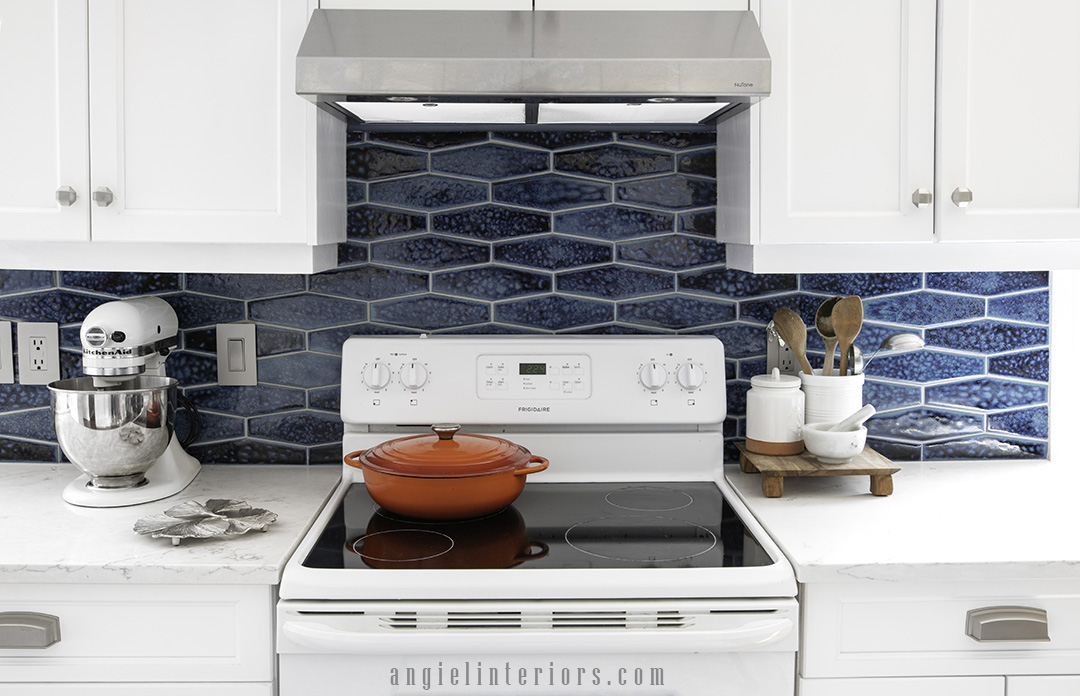 White kitchen stove with white cabinetry, quartz countertops and handmade ceramic tiles in navy blue