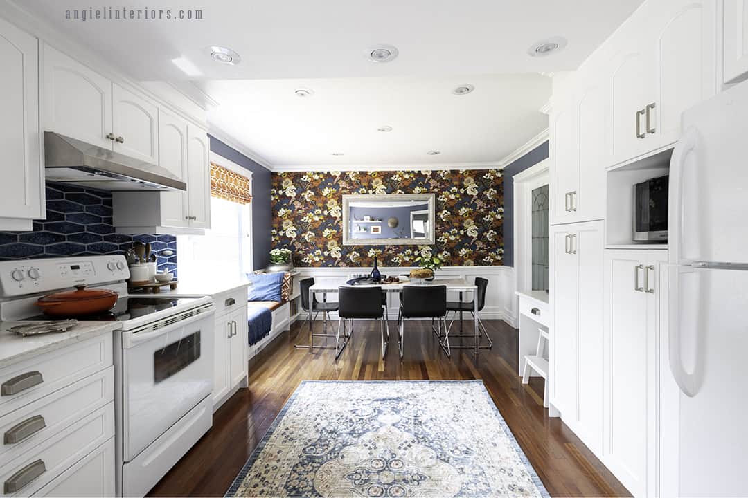 Big galley kitchen with white cabinets, Brazilian cherry hardwood floor and dining area with bold floral wallpaper in orange and blue
