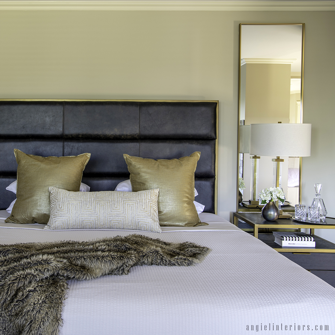 master bedroom decor in cream and gold with leather headboard, gold-framed mirrors and gold table lamp on a bedside table