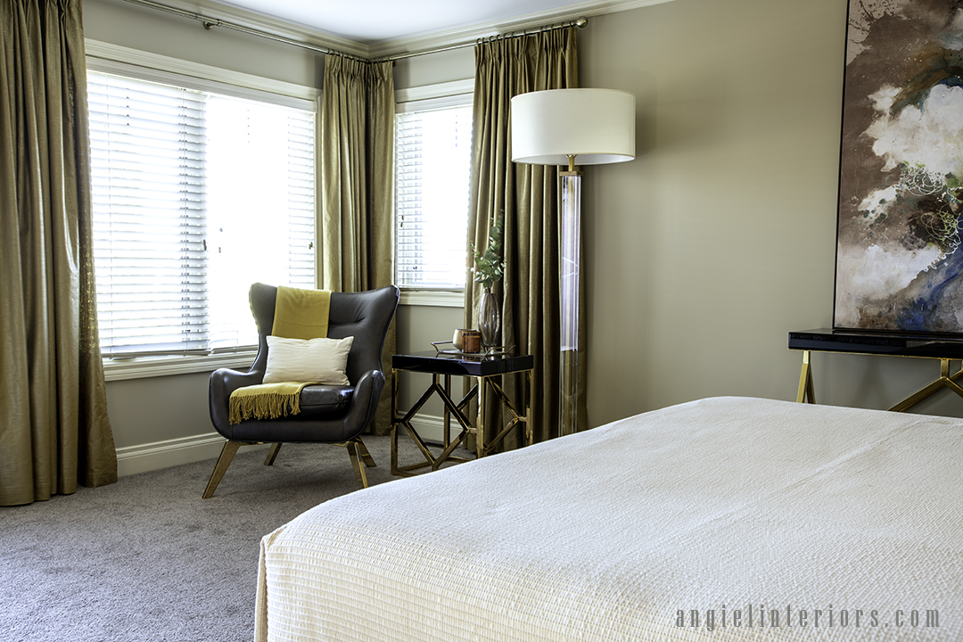 master bedroom corner with an armchair, side table and a floor lamp with gold linen curtains and white bedspread