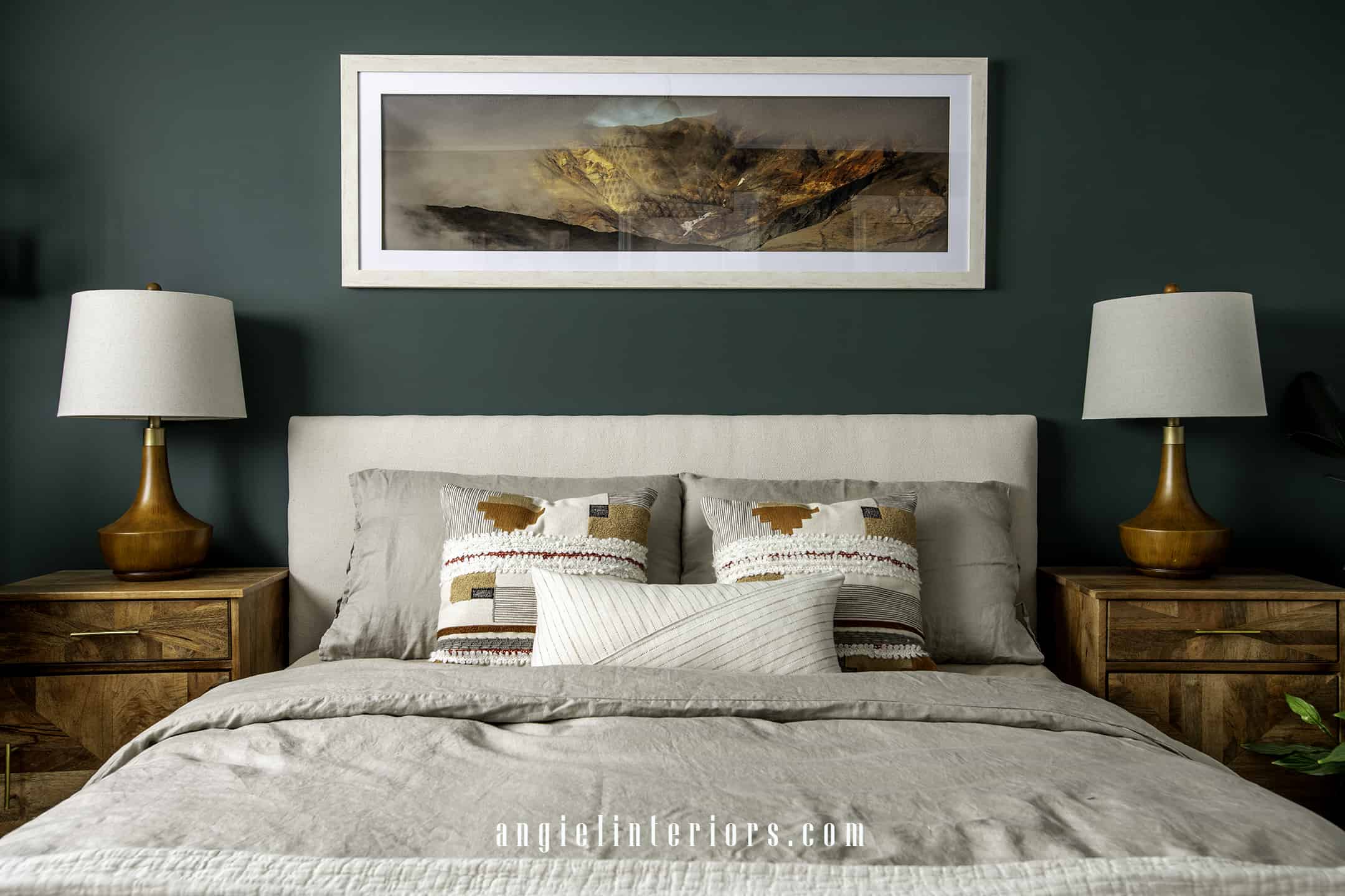 panoramic landscape photo over bed with ivory bedding and exotic wood nightstands and table lamps