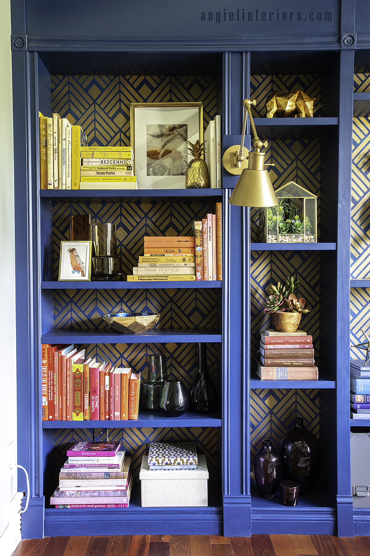 Blue built in bookcase with golden Art Deco stencil and brass swing arm sconce