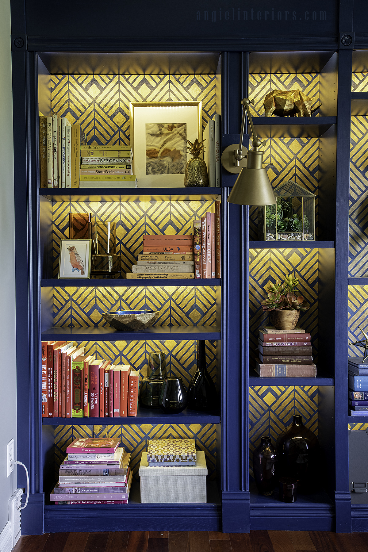 Blue built in bookcase with golden Art Deco stencil, LED lighting and brass swing arm sconce