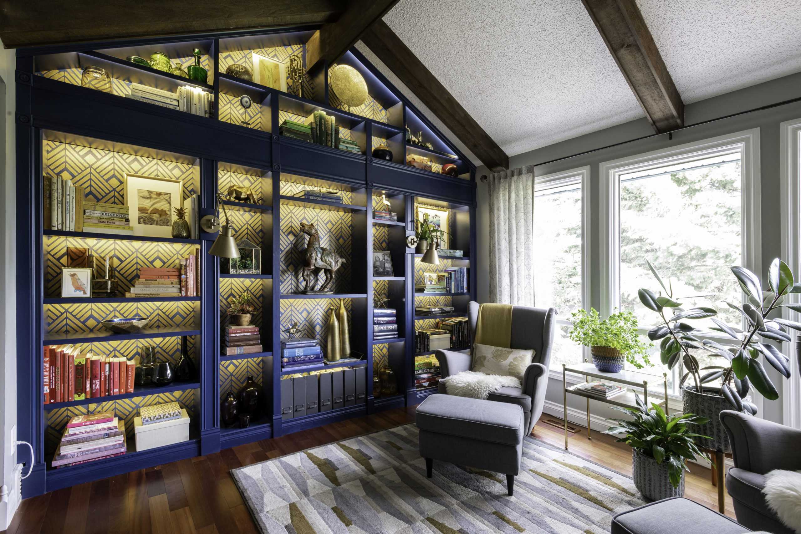 DIY built in library bookcase in blue with golden art Deco stencil and LED lights in a room with vaulted ceiling