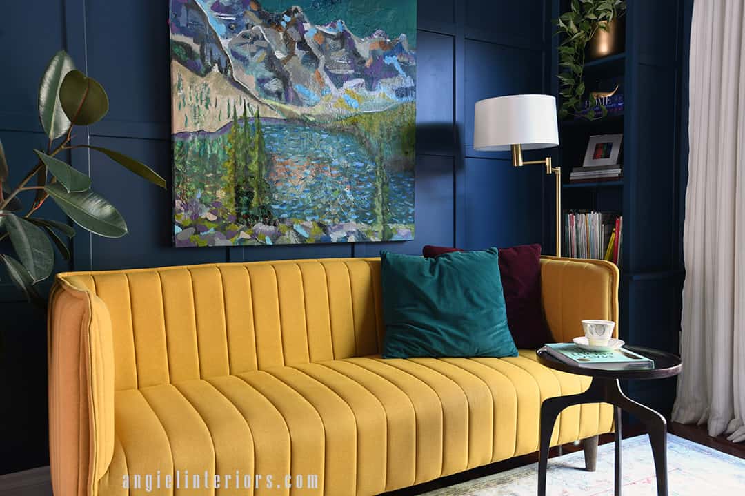 Painting of Moraine Lake on a blue grid wall above a yellow sofa