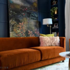 Living room with navy grid wall and built in bookcase, orange sofa and abstract painting