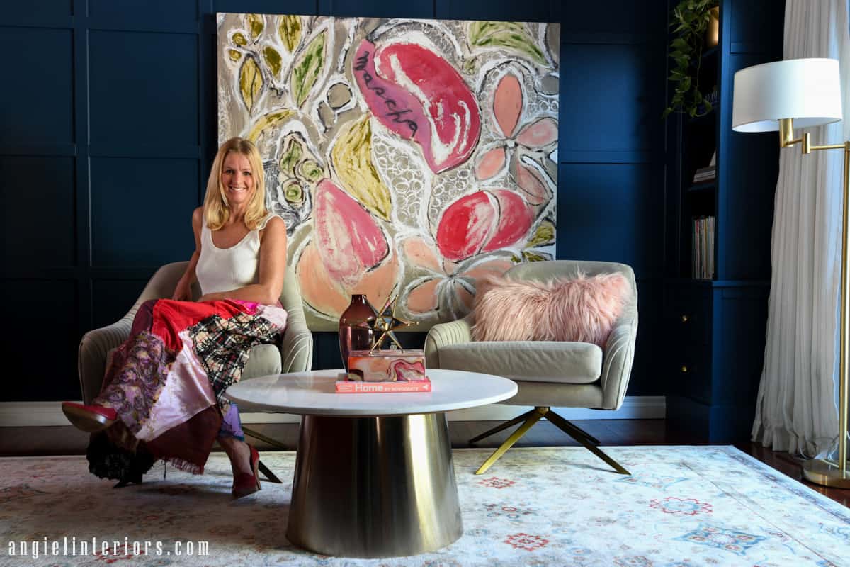 Living room with blue grid wall, built in bookcase, gray velvet swivel chairs and abstract painting in pink