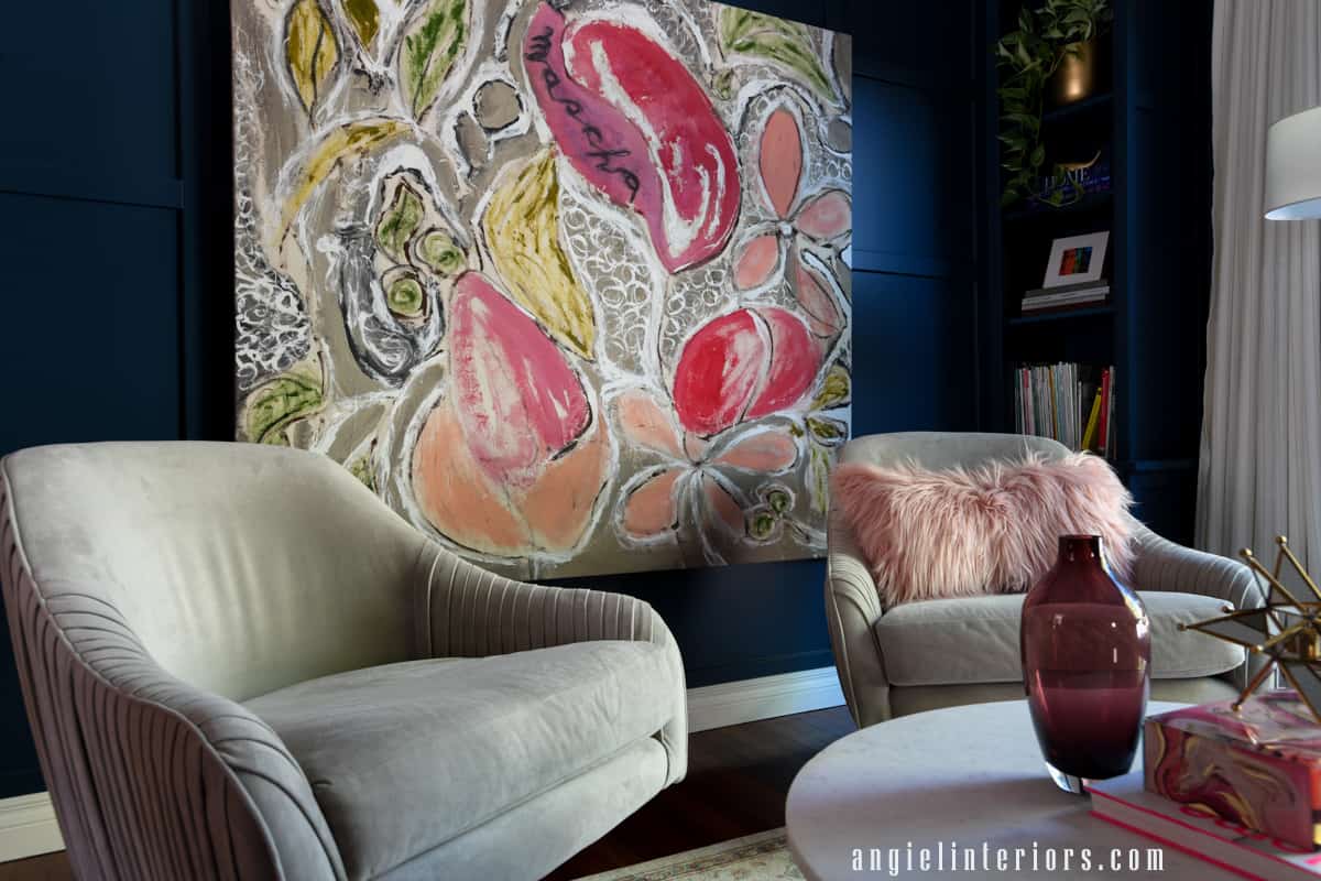 Living room with blue grid wall, built in bookcase, gray velvet swivel chairs and abstract painting in pink